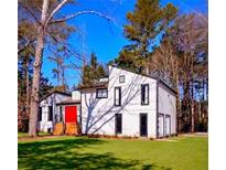 Striking white exterior elevation featuring a red front door and modern architectural details in wooded setting at 2645 Shadow Woods Ne Cir, Marietta, GA 30062