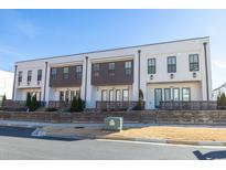 Three modern townhouses with white siding, dark brown accents, and private fenced patios at 896 Farmstead Rd, Suwanee, GA 30024