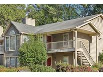 Tan two-story condo with a red door, wooden stairs, and landscaping at 2408 Country Park Se Dr, Smyrna, GA 30080