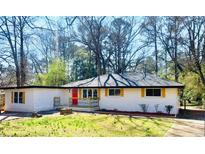 Charming ranch home with updated exterior, featuring a red door and landscaped lawn at 1807 W Austin Rd, Decatur, GA 30032