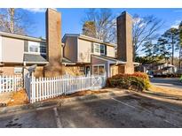 Two-story townhome with brick and siding exterior, white picket fence, and ample parking at 557 Summit Sw Ln, Marietta, GA 30008