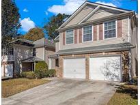 Tan two-story house with a two-car garage and manicured lawn at 1835 Roble Dr, Atlanta, GA 30349