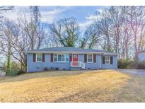 Ranch style home with blue exterior, red door, and landscaped lawn at 1927 Vicki Se Ln, Atlanta, GA 30316