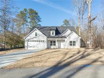 White farmhouse exterior with gray roof, two-car garage, and landscaped yard at 4392 Navajo Se Ln, Acworth, GA 30102