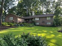 Beautiful brick home featuring manicured lawn, mature trees, and colorful flower beds at 747 Dogwood Cir, Norcross, GA 30071