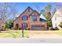 Charming stone-faced home with red shutters, manicured lawn, and a two-car garage at 4595 Carriage Walk Ln, Cumming, GA 30040