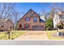 Charming stone home featuring a well-manicured lawn and two-car garage at 4595 Carriage Walk Ln, Cumming, GA 30040