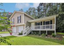 Tan house with a double garage and front porch at 3980 Carlton Cove Ct, Loganville, GA 30052