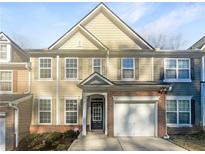 Two-story townhome with neutral siding, brick accents, and a two-car garage at 4154 Magnolia Glen Walk, Norcross, GA 30093