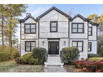 Two-story house with white brick and black trim, landscaping, and a paved walkway at 3007 Winding Sw Way, Lilburn, GA 30047