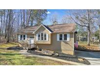 Tan house with white shutters, a wooden deck, and a landscaped yard at 15 Indian Woods Ne Dr, Rydal, GA 30171