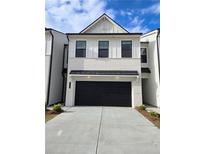 Two-story townhome with white brick exterior, black garage door, and landscaping at 1946 Westwind Street (Lot 132), Lawrenceville, GA 30043