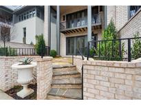 Stone steps lead to a patio with a brick wall and landscaping at 92 Sheridan Dr, Atlanta, GA 30305