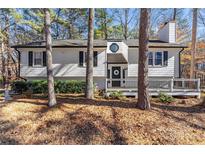 Charming ranch home with white siding, deck, and mature trees in the front yard at 2673 Mountain Brook Rd, Canton, GA 30114