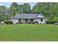 White house with gray roof, manicured lawn, and mature trees at 257 Regal Nw Dr, Lawrenceville, GA 30046