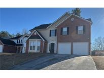 Brick two-story house with a three-car garage and manicured lawn at 2499 Tolliver Dr, Ellenwood, GA 30294