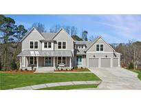 Charming two-story home with gray siding, metal roof, covered porch, manicured lawn, and attached two-car garage at 165 Grayton Ln, Roswell, GA 30075