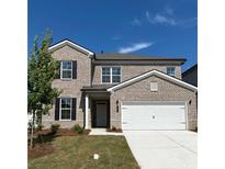 Two-story brick home with a white two-car garage and landscaped lawn at 4169 Wood Fern Ln, Buford, GA 30519