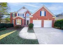 Brick two-story home with three-car garage and landscaped lawn at 8215 Aulden Pl, Cumming, GA 30041