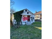 White bungalow with overgrown vines and graffiti, needing renovation at 654 English Nw Ave, Atlanta, GA 30318