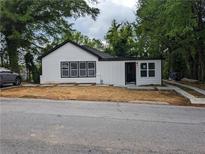 Newly renovated white house with black accents and a landscaped yard at 2624 Peyton Nw Rd, Atlanta, GA 30318