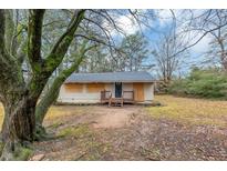 Ranch style house with boarded windows and mature trees in the front yard at 4175 Cottage Ln, Conley, GA 30288