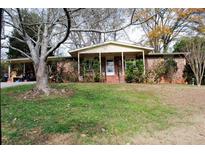 Brick ranch house with covered porch, driveway, and mature landscaping at 2499 Little John Se Trl, Marietta, GA 30067