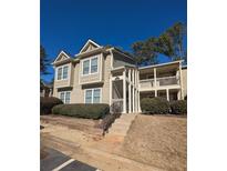 Two-story condo building with light beige siding, balconies, and landscaping at 21 Muncy Se Ct, Smyrna, GA 30080