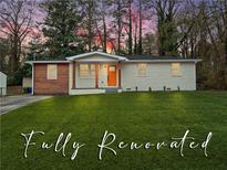 Beautifully renovated single-story home with an orange front door, updated columns, and a lush green lawn at 904 Fairburn Nw Rd, Atlanta, GA 30331
