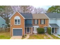 Charming brick townhome with well-maintained lawn and gray garage door offers great curb appeal at 8045 Woodlake Dr, Riverdale, GA 30274