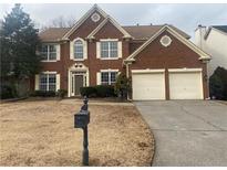 Brick two-story house with a three-car garage and well-maintained lawn at 1142 Drewsbury Se Ct, Smyrna, GA 30080