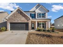 Two story home with brick and white siding, gray garage door, and landscaping at 210 Omega Ct, Dallas, GA 30157
