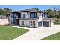 Two-story modern home with white brick, dark trim, and a three-car garage at 553 Versailles Dr, Auburn, GA 30011