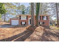 Charming two-story brick home featuring a well-kept front yard and attached garage with a concrete driveway at 5938 Baywood Ln, Riverdale, GA 30296