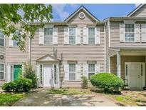 Tan two-story townhouse with green door, landscaping, and driveway at 142 Benfield Cir, Cartersville, GA 30121