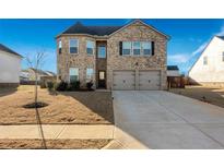 Two-story brick home with a two-car garage and landscaped yard at 909 Teabiscuit Way, Mcdonough, GA 30253