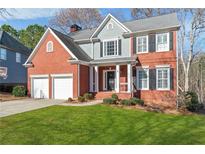 Two-story brick home with gray siding, shutters, and a well-manicured lawn at 8630 Amsbury Way, Cumming, GA 30041