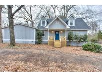 Gray house with blue door, wooden stairs, and landscaping at 23 Club Dr, Locust Grove, GA 30248