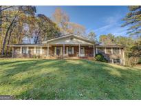 Charming brick home with a welcoming front porch and lush green lawn at 15 Wehunt Dr, Ellenwood, GA 30294
