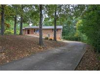 Brick home with an inviting front porch and a long driveway through a treed yard at 72 Bishop Nw Dr, Cartersville, GA 30121