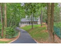 Charming home featuring a stone facade, black shutters, and a long, winding driveway through a lush green landscape at 4540 Club Valley Ne Dr, Atlanta, GA 30319