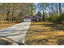 Charming brick home features a large driveway, attached two car garage, and a well-maintained front yard at 20 Trace Ct, Covington, GA 30016