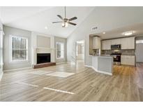Bright open-concept living room featuring a fireplace, ceiling fan, and hardwood flooring at 20 Trace Ct, Covington, GA 30016