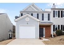 Two-story townhome with gray siding, brick accents, and a white garage door at 132 Timber Mist Ln, Lawrenceville, GA 30045
