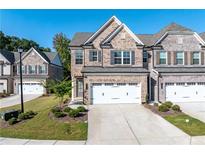 Two-story brick townhome with a two-car garage and manicured lawn at 2254 Morgan Place Dr, Buford, GA 30519