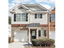 Attractive two-story townhome with brick and stone accents, a two-car garage, and landscaping at 3000 Heritage Villa Dr, Lithonia, GA 30038