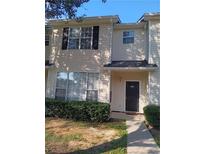 Tan two-story townhome with black shutters, a walkway, and landscaping at 114 Odyssey Turn, Conyers, GA 30012