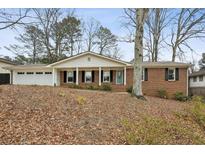 Brick ranch house with attached garage and mature trees at 2947 Dunnington Cir, Chamblee, GA 30341