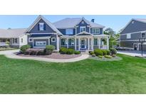 Stunning home featuring a manicured lawn, walkway, lush shrubbery, and covered front porch at 535 Crested Hawk Rdg, Canton, GA 30114