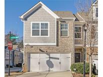 Two-story townhome with gray siding, brick accents, and a two-car garage at , Stone Mountain, GA 30083